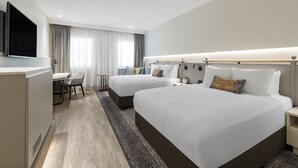 Hotellihuone, jossa on kaksi sänkyä, työpöytä ja televisio.