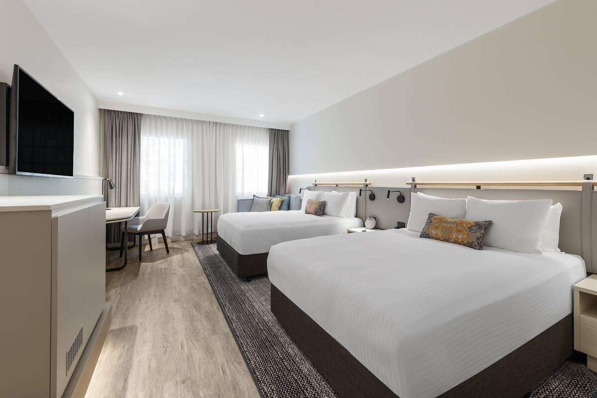 Een hotelkamer met twee bedden, een bureau en een televisie.