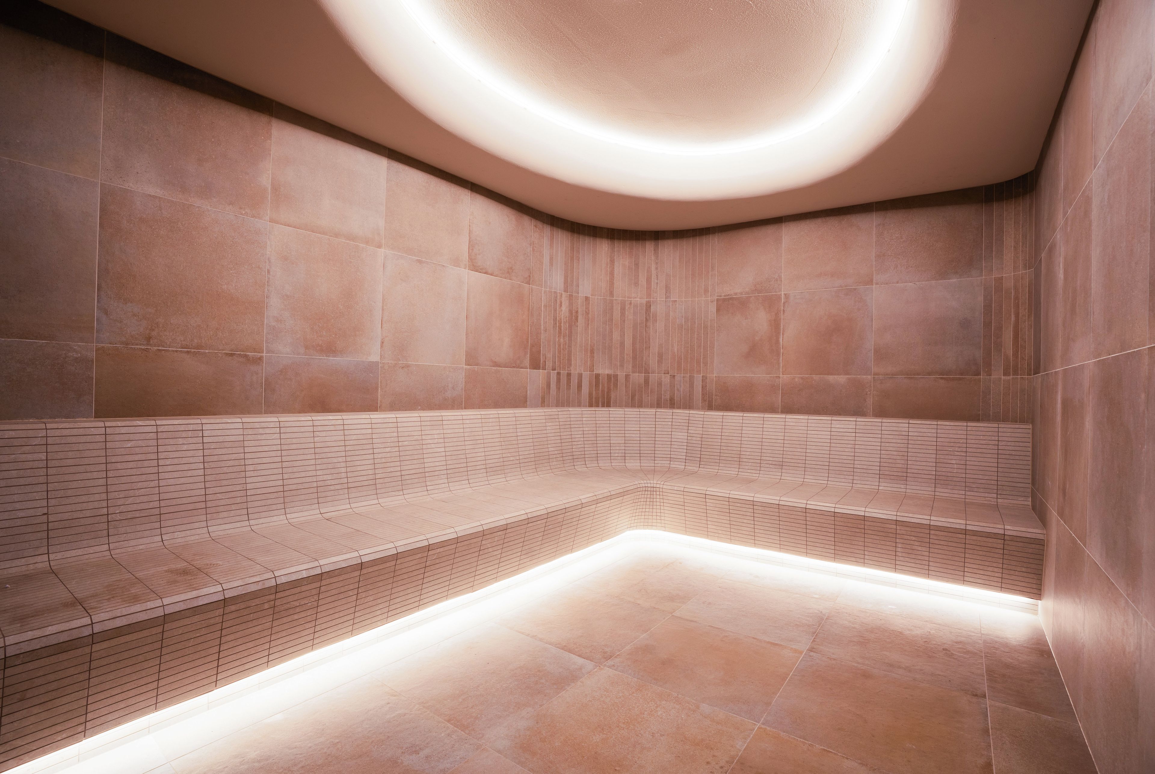 A modern, well-lit spa area with a curved bench and tiled walls.