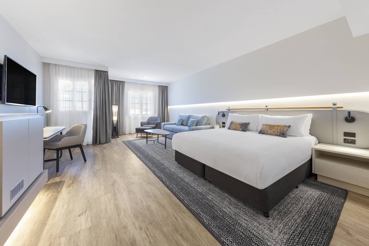 Een moderne hotelkamer met een groot bed, een bureau, een stoel en een televisie.