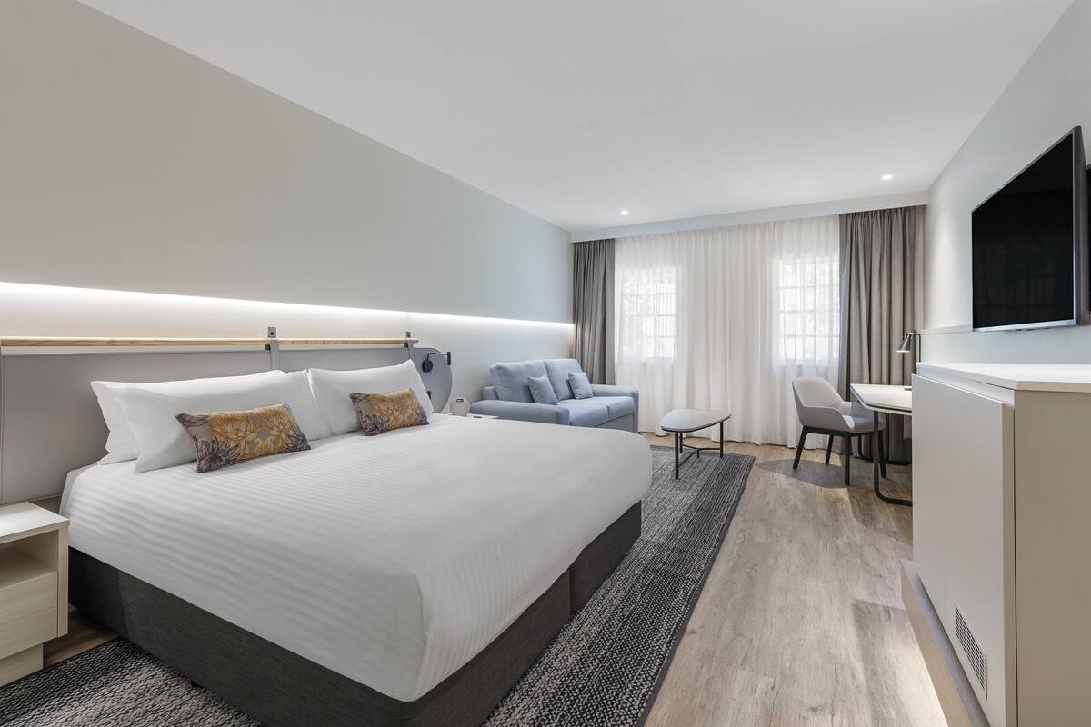 Een moderne hotelkamer met een groot bed, een bureau en een televisie.