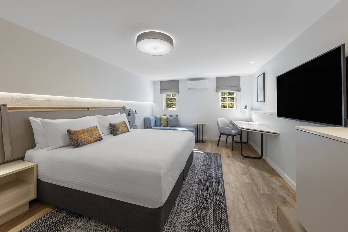 Een moderne hotelkamer met een groot bed, een bureau en een televisie.