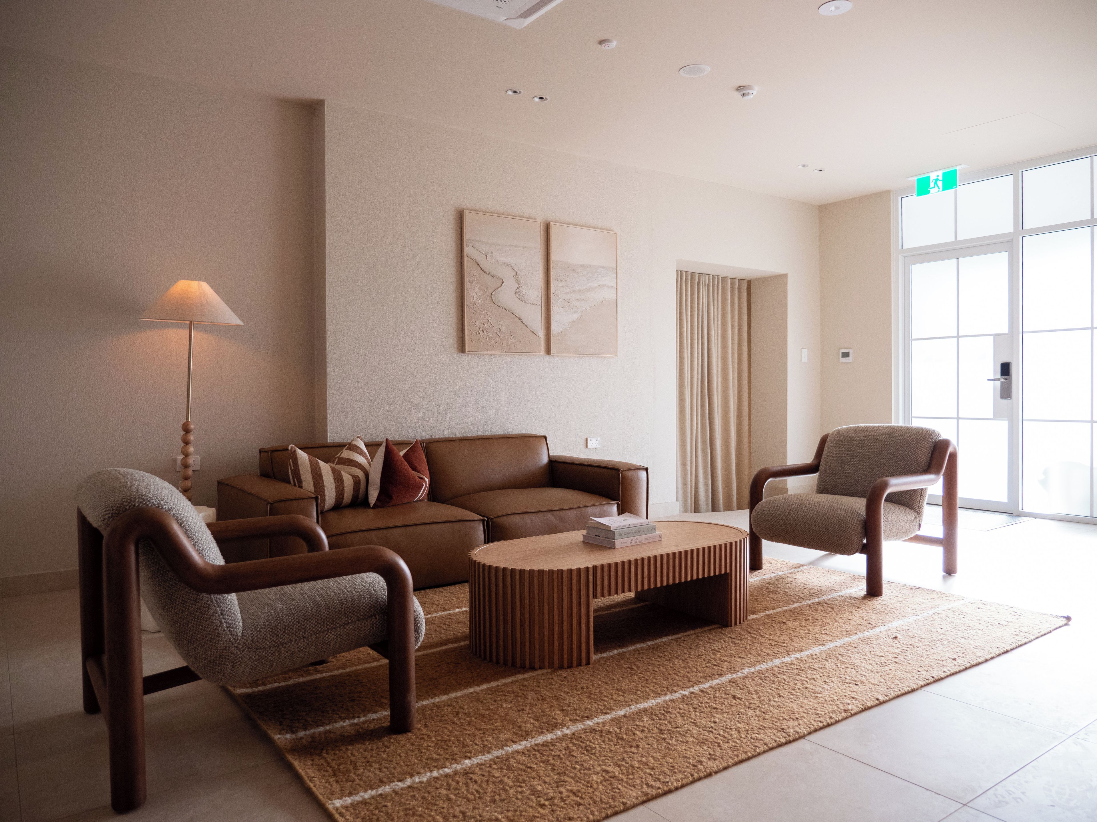 Un salon moderne comprenant un canapé, deux fauteuils, une table basse et une lampe.