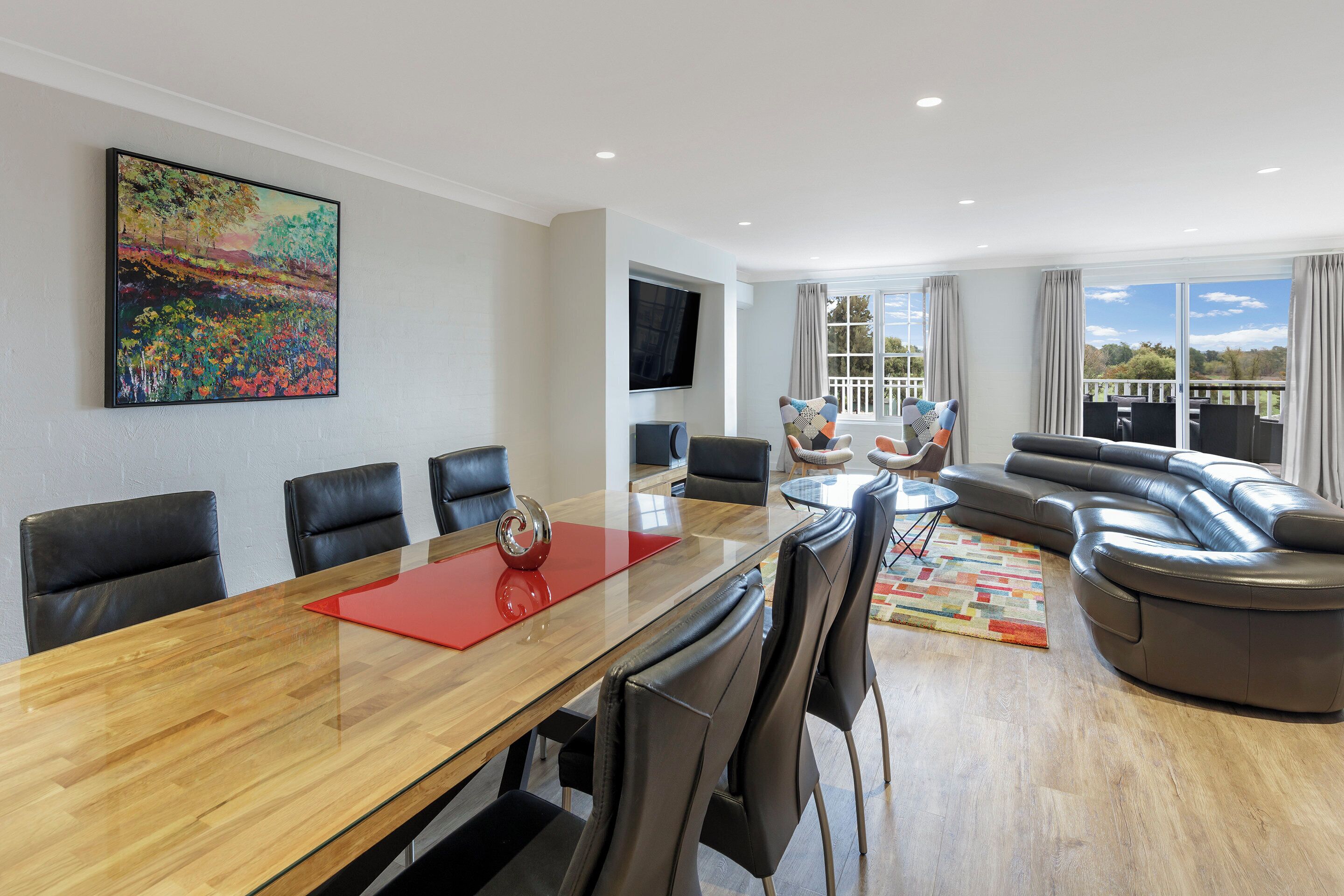 Una sala de estar moderna con un sofá grande, una mesa de comedor con sillas y un cuadro en la pared.
