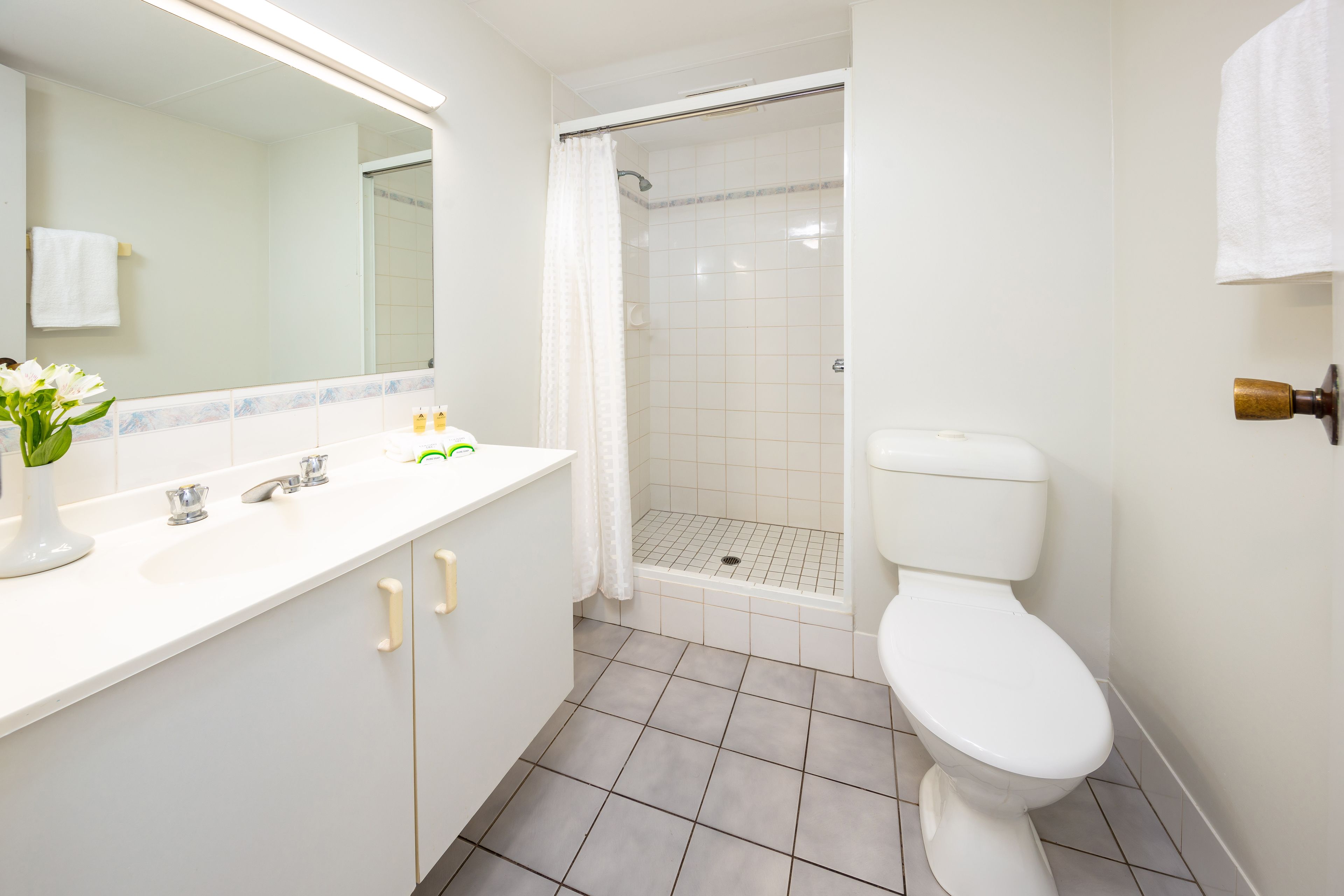 Baño con lavamanos, espejo y retrete blancos.