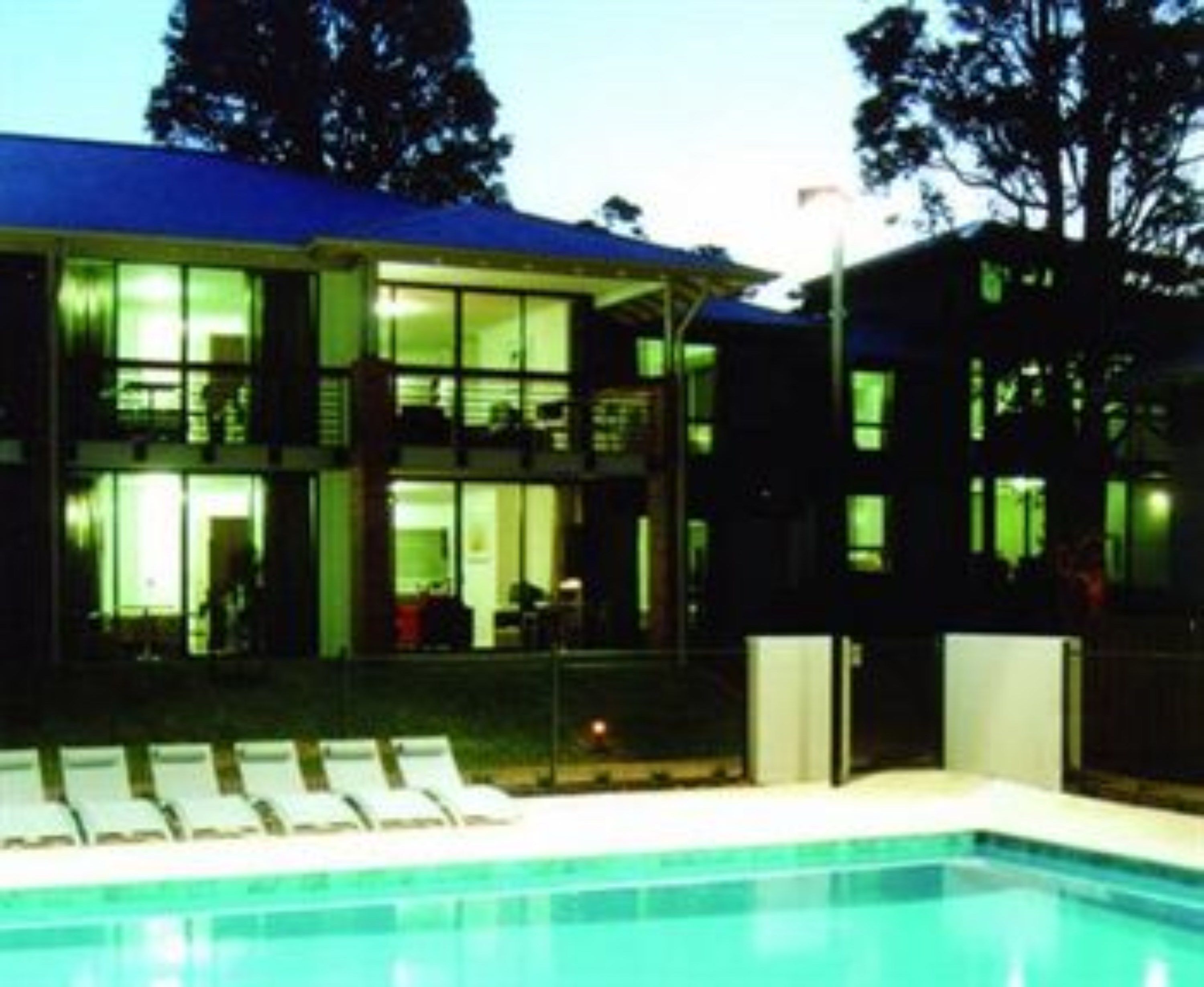Un edificio de dos plantas con una piscina al frente.