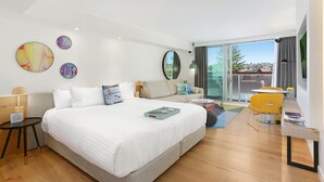 Una habitación de hotel moderna con una cama grande, un escritorio, una silla y un balcón con vistas.