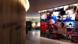 Un moderno vestíbulo de hotel con un mostrador de recepción de madera y una pared decorada con diversas fotografías.