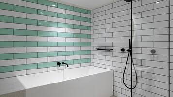 A modern bathroom with a white bathtub, a glass-enclosed shower, and a tiled wall with green and white tiles.