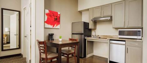 Cocina compacta con comedor, refrigerador, microondas y lavavajillas.