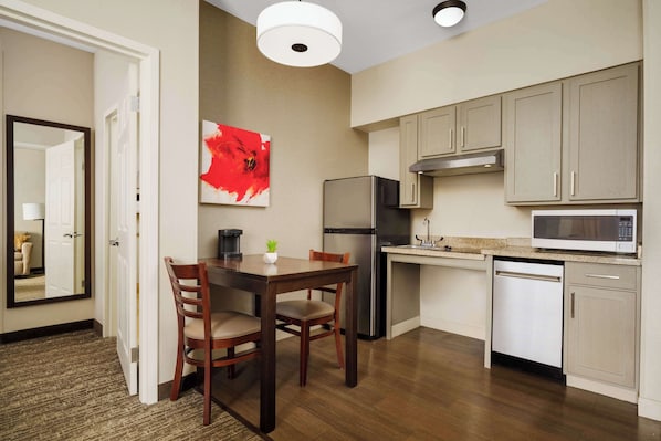 A compact kitchen with a dining area, a refrigerator, microwave, and a dishwasher. - Homewood Suites by Hilton Rochester/Henrietta (Rochester)