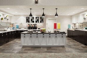 A modern kitchen with a central island, dark cabinetry, and pendant lighting.