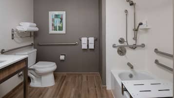 A modern bathroom with a toilet, sink, shower, and grab bars.
