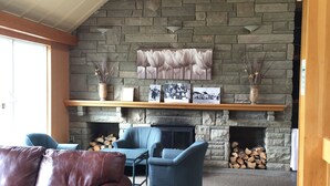 Un salon chaleureux avec une cheminée en pierre, des meubles en cuir bleu et marron, et un sol carrelé.