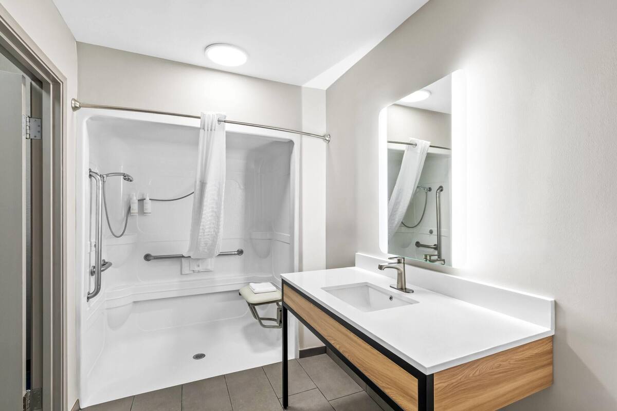A modern bathroom with a shower, a sink, and a mirror.