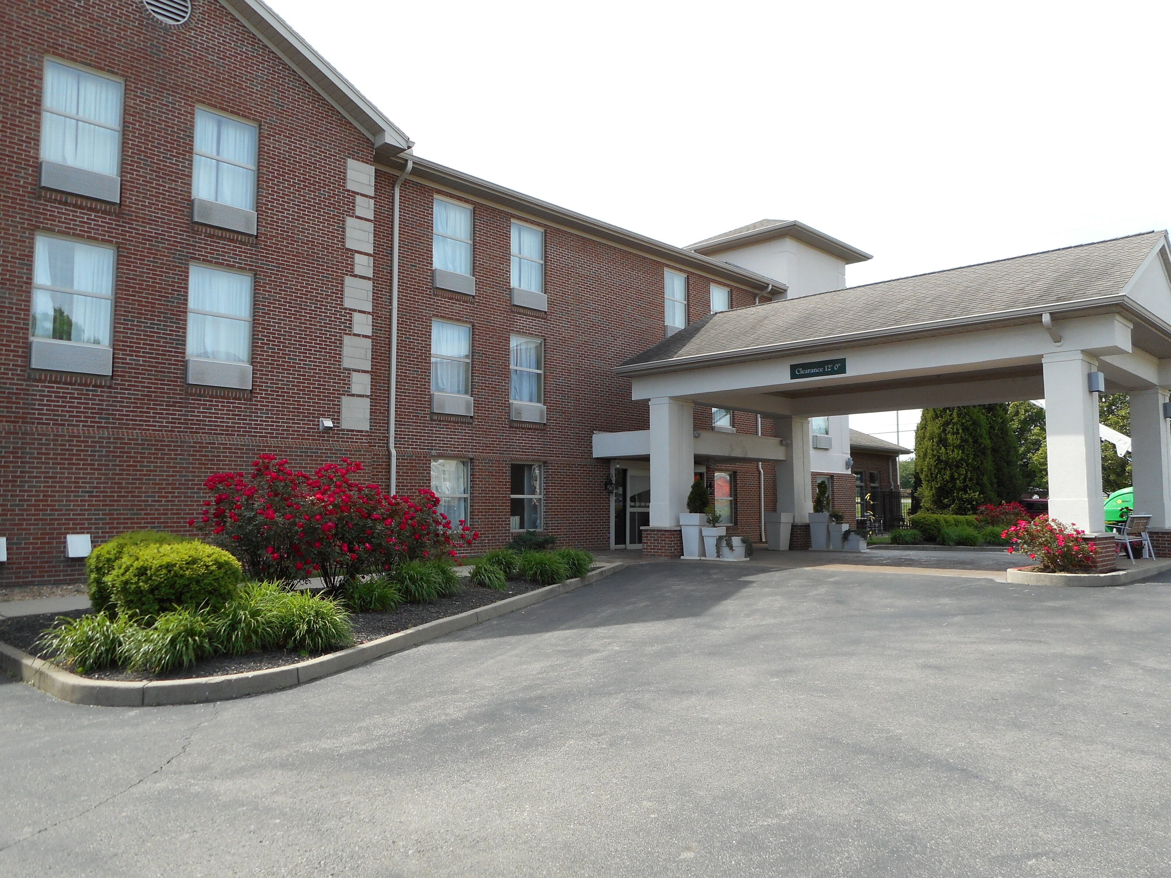 A multi-story brick building with a covered entrance and a parking area.