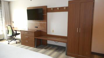A hotel room with a bed, a desk with a chair, a TV, and a wardrobe.