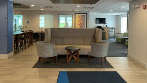 A modern lounge area with a sofa, two armchairs, a small table, and a TV screen. - Holiday Inn Express Fairfield by IHG (Fairfield)