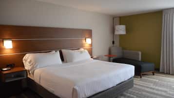 A hotel room with a large bed, a nightstand, a chair, and a lamp.