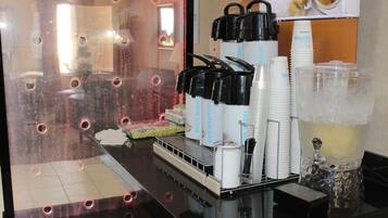 Una estación de bebidas con varios dispensadores, una máquina de café y una jarra grande de café helado.