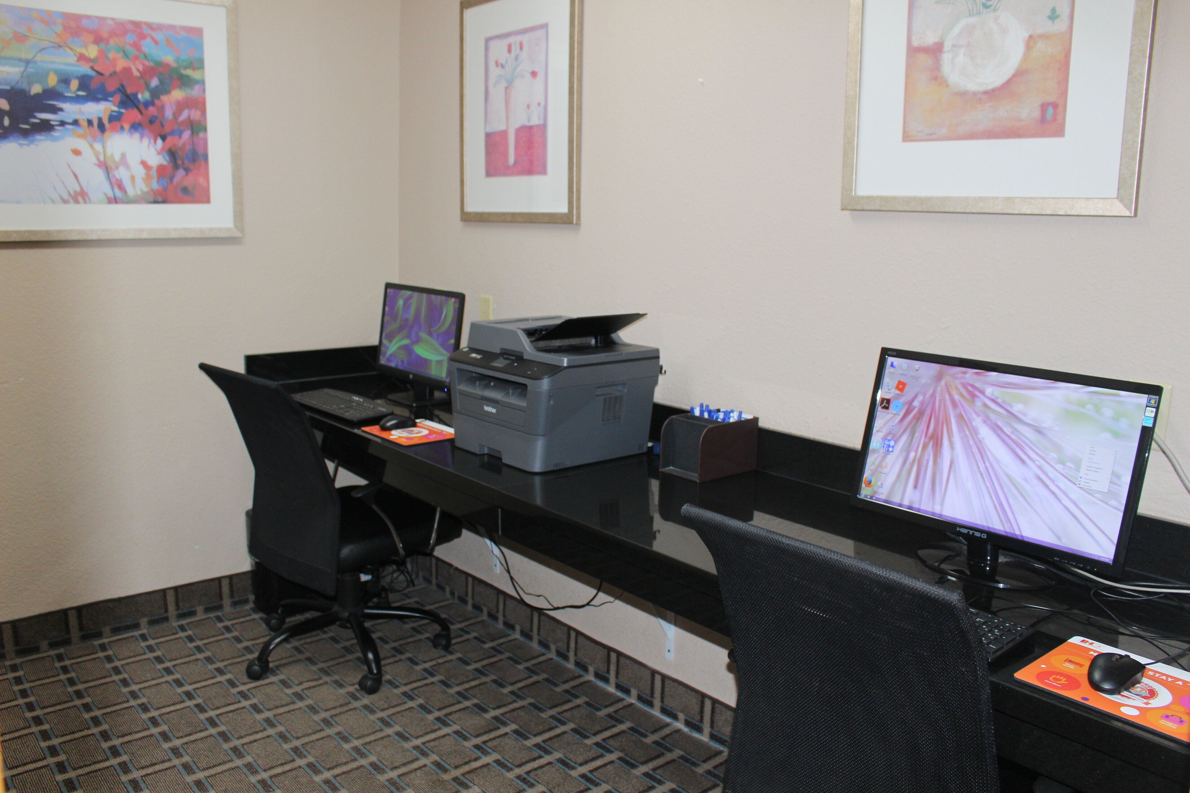 A workspace with two computers, a printer, and a chair.