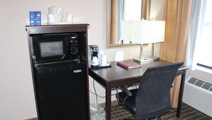 A compact hotel room with a kitchenette, including a microwave, coffee maker, and a small trash bin. - Holiday Inn Express Kansas City-Liberty by IHG (Kansas City)