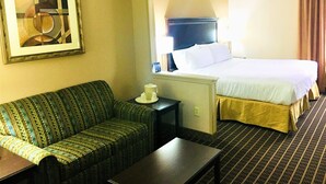 A hotel room with a bed, a sofa, a table, and a painting on the wall. - Holiday Inn Express Kansas City-Liberty by IHG (Kansas City)