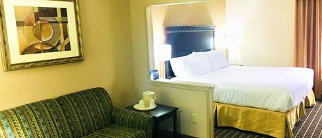 Een hotelkamer met een bed, een bank, een tafel en een schilderij aan de muur.