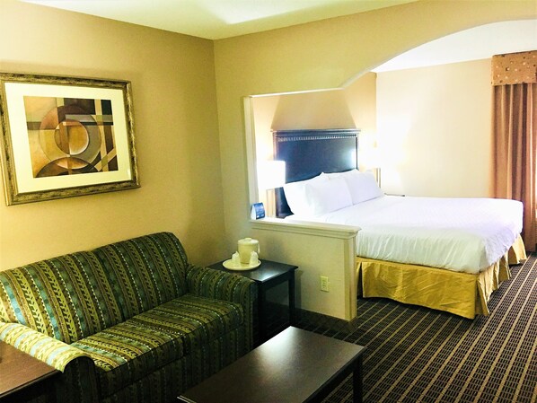 A hotel room with a bed, a sofa, a table, and a painting on the wall. - Holiday Inn Express Kansas City-Liberty by IHG (Kansas City)