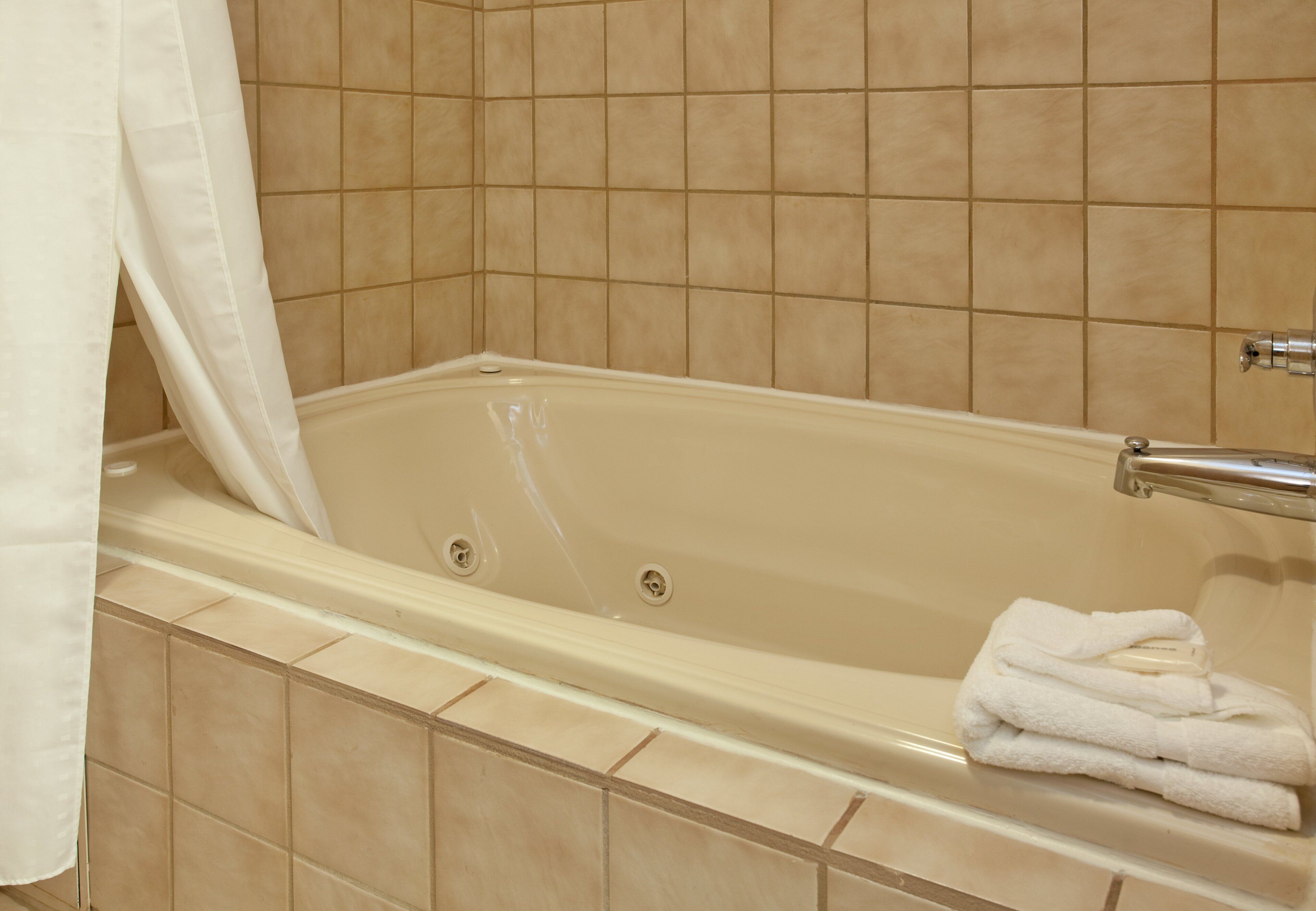 A bathtub with a shower curtain, a towel, and a faucet.