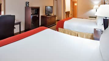 Una habitación de hotel con dos camas, un escritorio con computadora, televisor y cafetera.