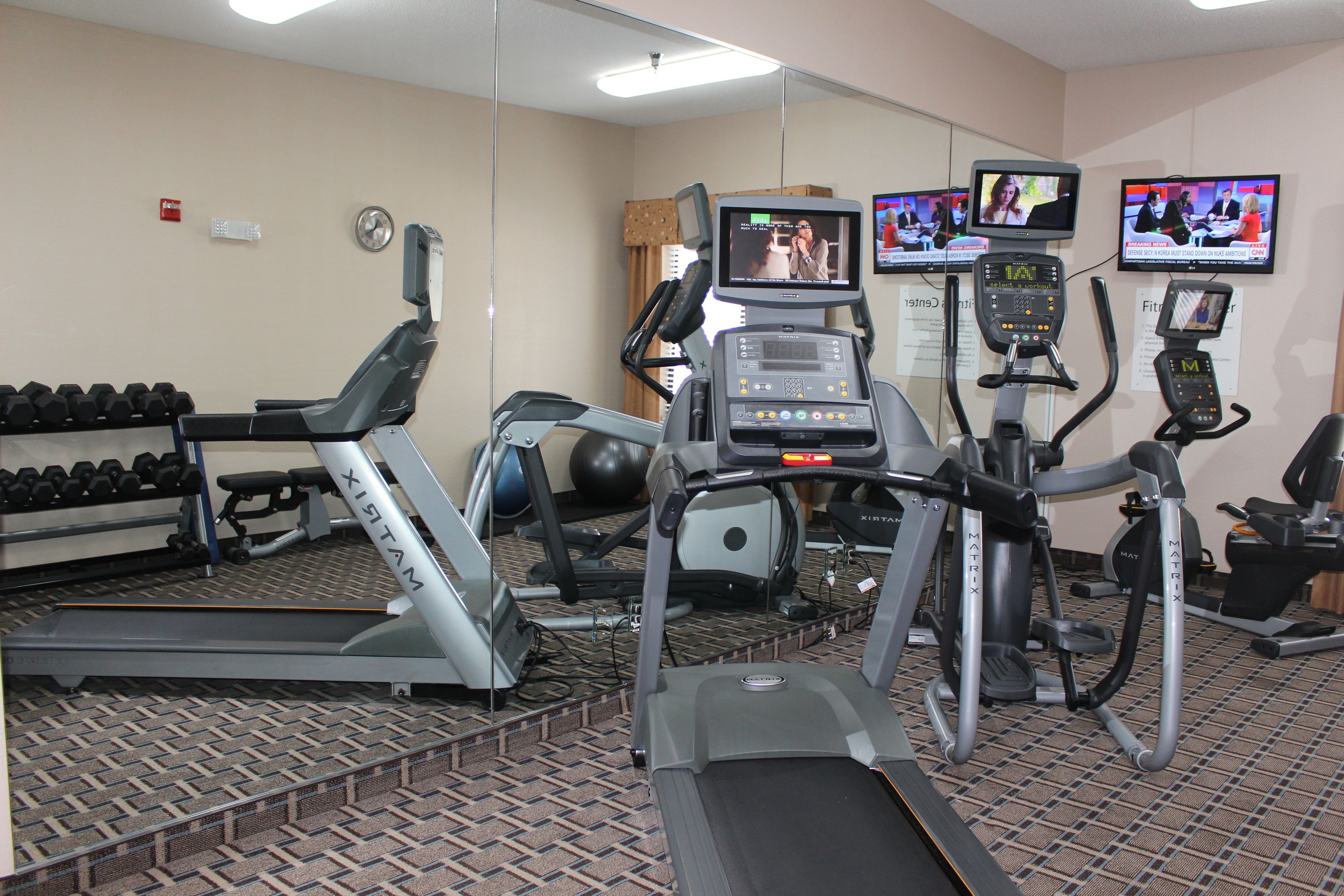 Un gimnasio con cintas de correr, elípticas y mancuernas.