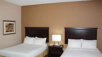 A hotel room with two beds, a nightstand with a lamp, and a framed picture on the wall.