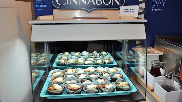 A display case filled with various pastries and a sign above it that reads "CINNABON". - Holiday Inn Express Kansas City-Liberty by IHG (Kansas City)