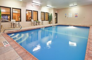 Une piscine avec un bord carrelé, un poste de surveillance pour le sauveteur et un panneau indiquant qu’il est interdit de plonger.