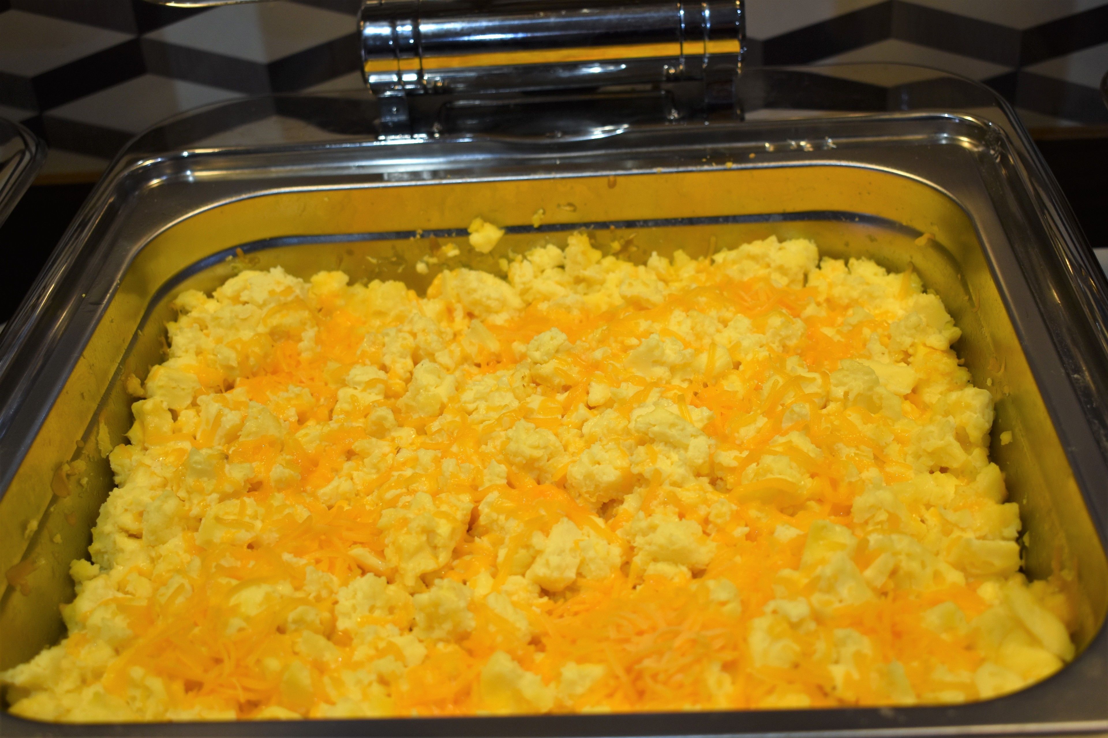 A buffet with scrambled eggs and cheese.