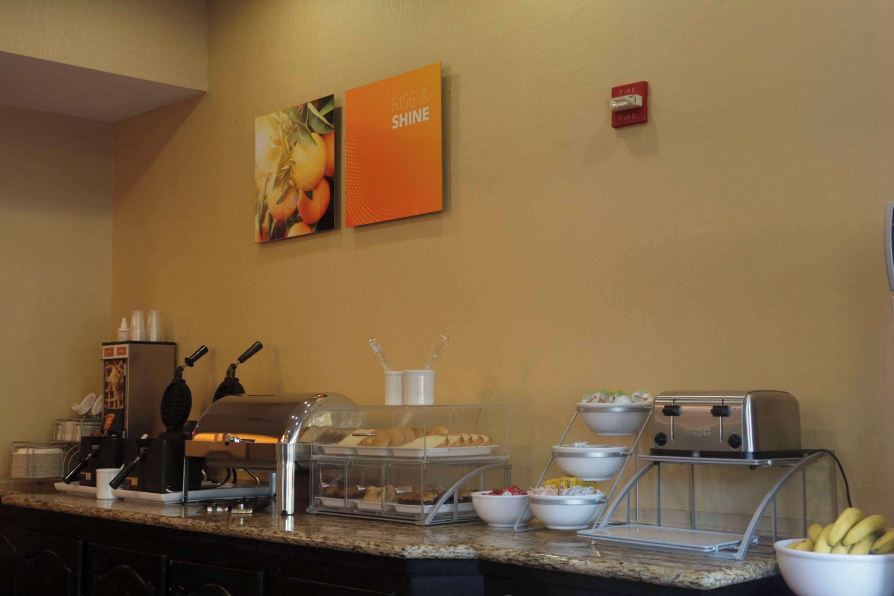A breakfast bar with a coffee machine, toaster, and various food items.