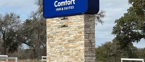 A Comfort Inn & Suites sign on a stone pillar with a blue background and a crescent moon logo.