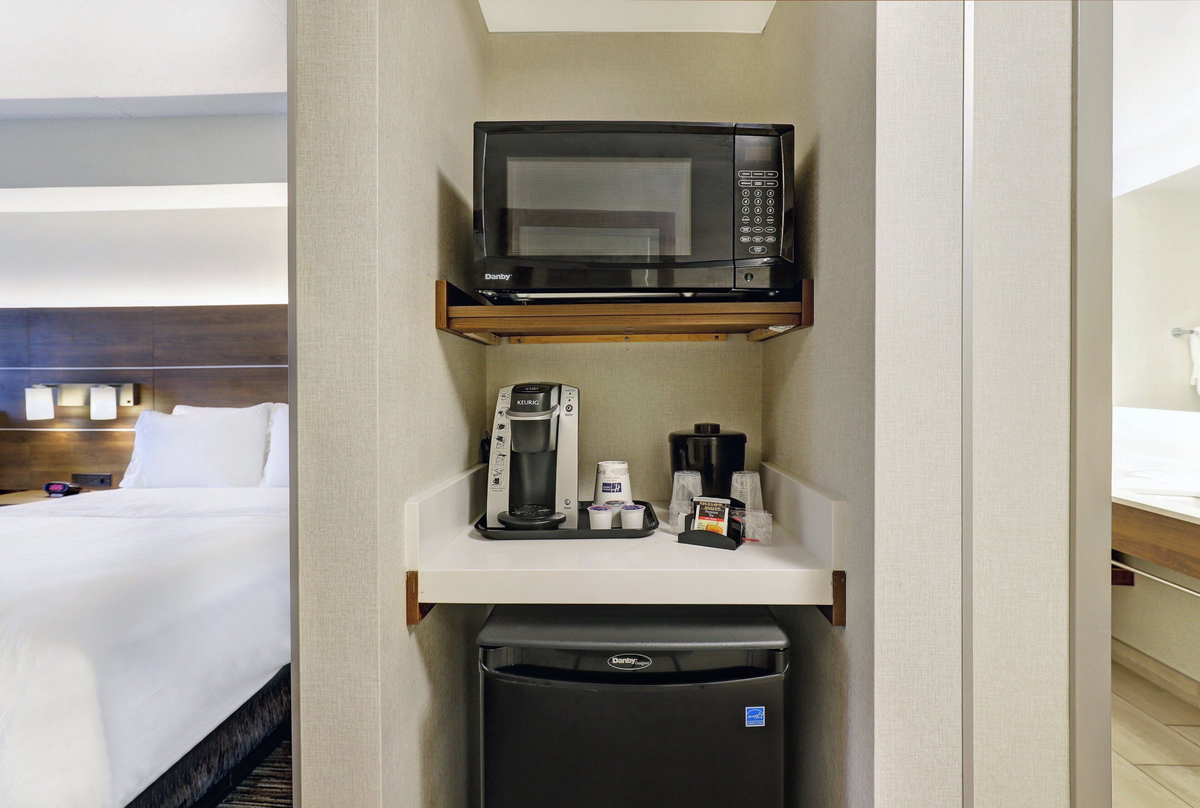 A hotel room with a minibar containing a microwave, coffee maker, and refrigerator.