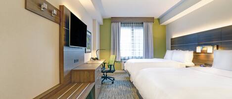 Habitación de hotel con cama, escritorio, silla, televisión y ventana con cortinas.