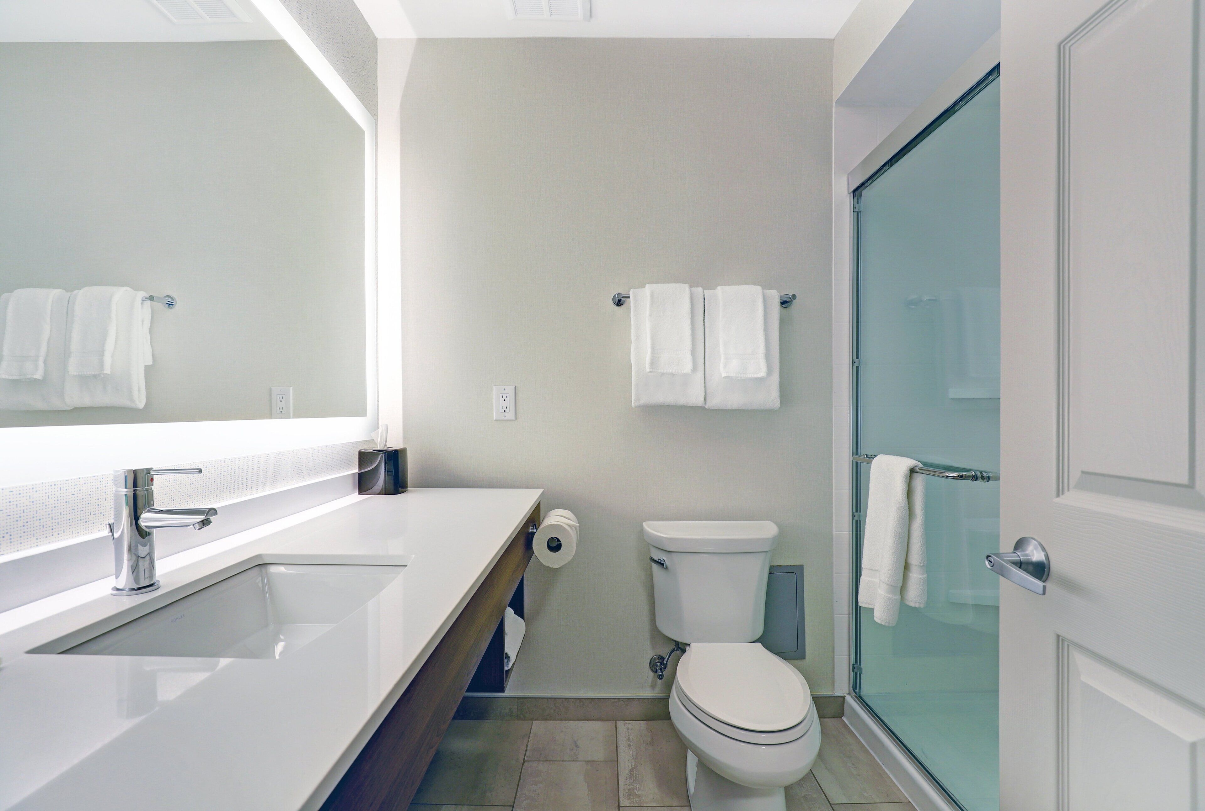 A modern bathroom with a white sink, toilet, and glass shower enclosure.