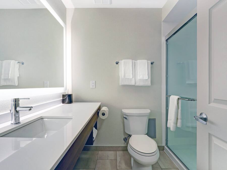 A modern bathroom with a white sink, toilet, and glass shower enclosure.
