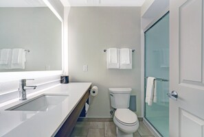 A modern bathroom with a white sink, toilet, and glass shower enclosure.