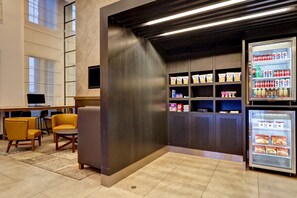 A hotel lobby with seating, a refrigerator stocked with beverages, and a wall-mounted television. - Holiday Inn Express Whitby by IHG (Whitby)