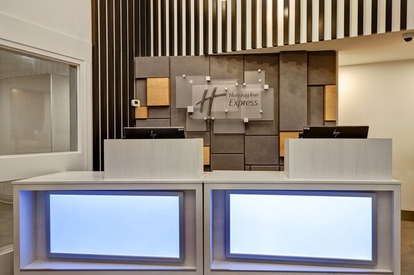 A reception desk with a modern design, a sign for Holiday Inn Express, and two laptops on the counter. - Holiday Inn Express Whitby by IHG (Whitby)