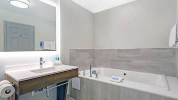 Un bagno moderno con un mobile bagno in legno, uno specchio grande, una vasca e un water.