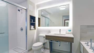 Une salle de bain moderne avec une douche à parois de verre, des toilettes, un lavabo avec un miroir au-dessus et un meuble-lavabo avec un porte-serviettes.