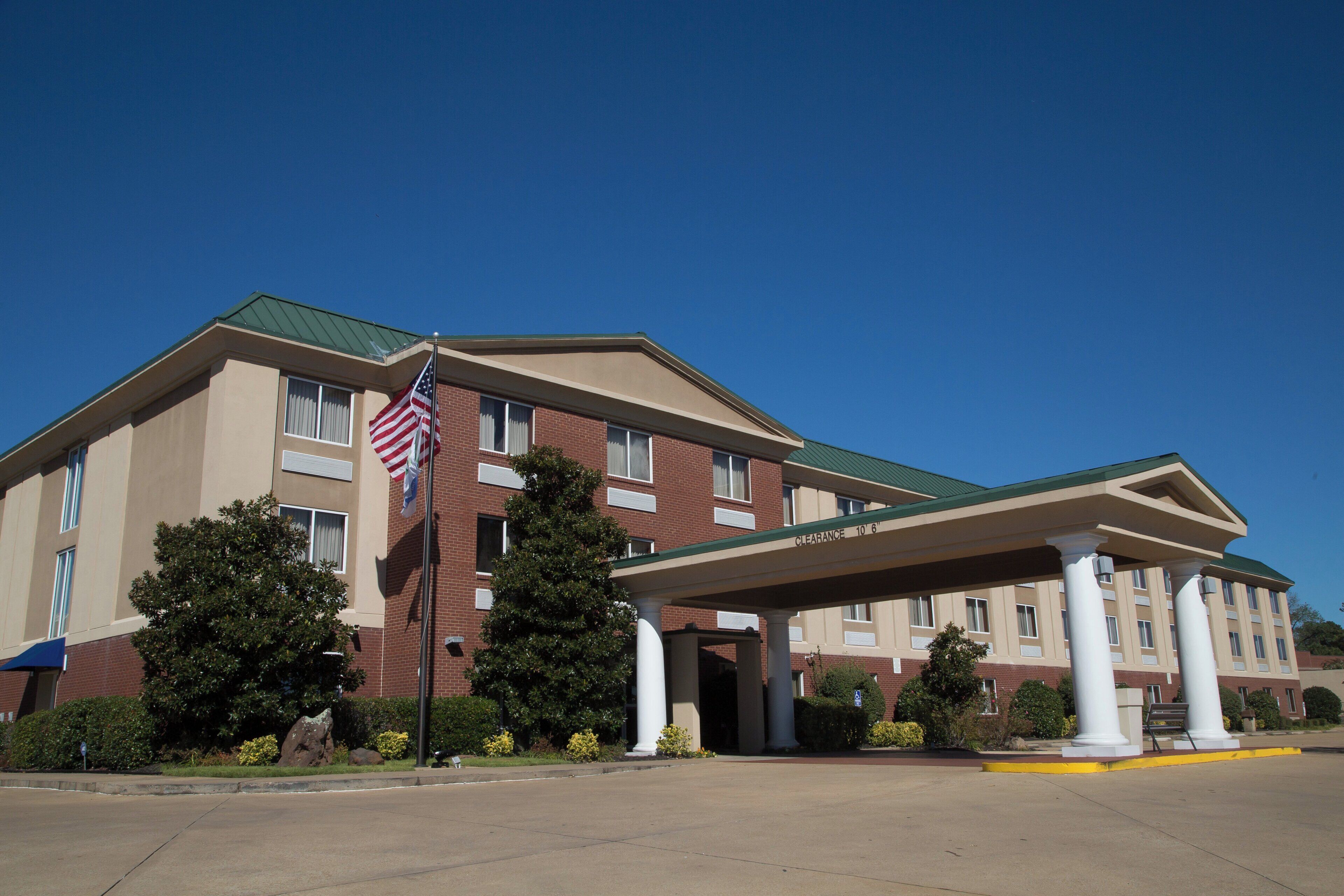 A hotel with a covered entrance, a flag, and a clear sky.