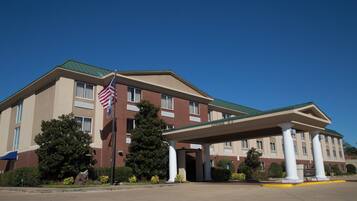 A hotel with a covered entrance, a flag, and a clear sky.