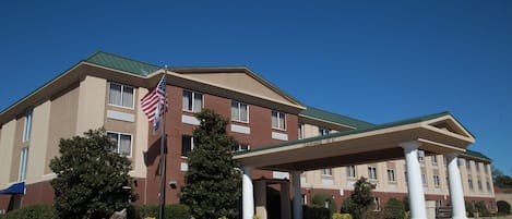 Un hotel con un acceso cubierto, una bandera y cielo despejado.